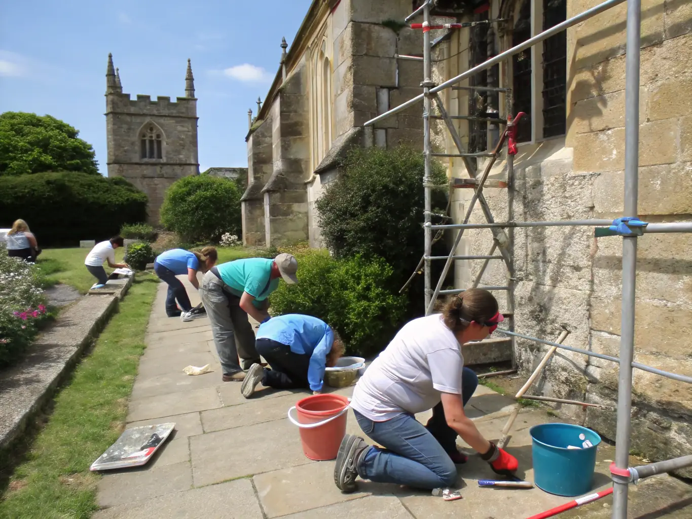 A photograph showcasing a group of volunteers participating in a hands-on workshop on cleaning and preserving historical artifacts, set within the basilica's historical context.